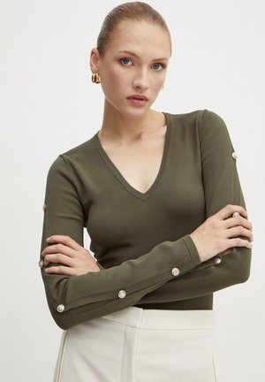 Maglietta verde oliva a maniche lunghe con scollo a V, design aderente e dettagli decorativi con bottoni lungo le maniche. Tessuto liscio e elasticizzato.