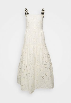 Robe blanche sans manches avec broderie florale en œillet et bretelles rayées noir et blanc.