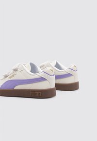 Zapatillas blancas y moradas con un upper de cuero suave, acentos de malla y suela de goma marrón. Cuenta con una correa de gancho y bucle y detalles del logo.