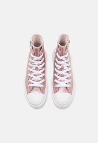 Para różowych, brokatowych sneakersów za kostkę z białymi sznurowadłami i gumowymi podeszwami, widzianych z góry na jednolitym białym tle.