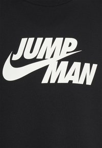 T-shirt di cotone nero con bold testo bianco "JUMP MAN" e l'iconico design dello Swoosh Nike. Texture liscia, scollo rotondo.