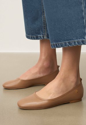 Balerini bej din piele netedă, cu vârf rotund, design minimalist și un mic accent cu logo auriu pe călcâi.