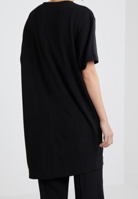 Svart oversized t-shirt med korta ärmar, rund hals och rak nederkant. Mjuk tyg med en slät yta och minimal detaljer.