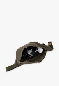 Olive green canvas bag with a zipper, containing a camera, sunglasses, and earbuds, featuring a strap and a flat, rounded shape.