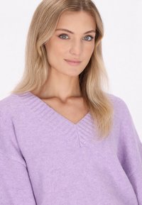 V-Ausschnitt Strickpullover in helllila, mit gerippten Details am Kragen und einem lässigen Schnitt. Hergestellt aus weichem, strukturiertem Stoff.