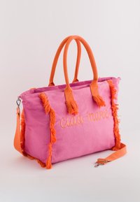 Rosa Canvas-Shopper mit orangen Fransen, Griffen und Riemen. Mit "ciao mare" in Orange bestickt. Geräumiges und strukturiertes Design.