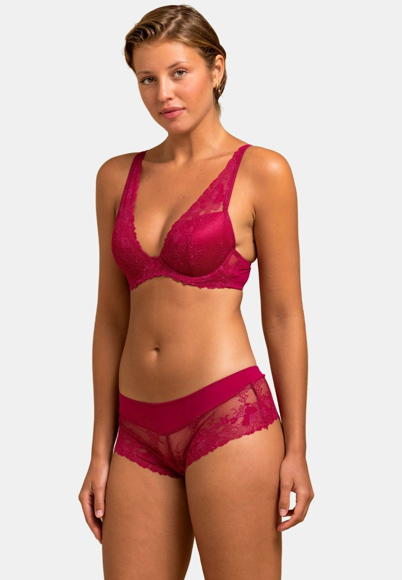 Soutien-gorge en dentelle bordeaux avec un décolleté en V profond et de larges bretelles, associé à des shortys en dentelle transparente assortis avec une taille solide et des accents floraux.