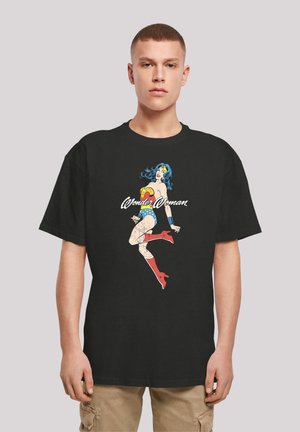 Black cotton t-shirt featuring a graphic of Wonder Woman. The design includes vibrant colors, with red and blue accents, and distressed details.