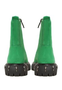 Groene suède enkellaarsjes met een ritsluiting, met een textuur zwarte plateauzool en metalen accenten aan de basis.