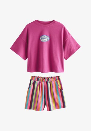 Magenta široký top s krátkym rukávom s logom "Tropical Bananas" a elastické šortky v páse s vertikálnymi viacfarebnými pruhmi a bočnými vreckami.