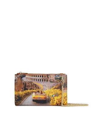 Borsa clutch gialla convertibile che percorre una strada fiancheggiata da fiori gialli verso il Colosseo a Roma, con tracolla a catena dorata.