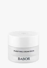 Opak vit krämburk med en glänsande yta, genomskinlig botten och ett platt, vitt lock. Texten på burken lyder "Purifying Cream Rich" och "BABOR."