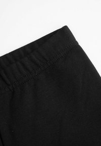 Czarna bawełniana tkanina o gładkiej teksturze, z elastycznym pasem i płaskimi szwami wzdłuż krawędzi.