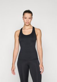 Svart ärmlös tanktopp i elastiskt material, med rund halsringning och figurnära design, i kombination med svarta leggings. Slät textur.