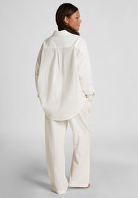 Witte textuur oversized overhemd en bijpassende broek set, met een kraaglijn, lange mouwen en een relaxte pasvorm.