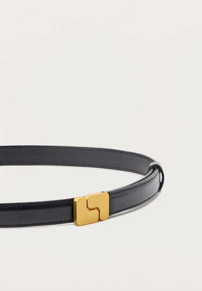 Μαύρη ζώνη από δέρμα με χρυσή γεωμετρική αγκράφα, απλωμένη επίπεδη πάνω σε απλό λευκό φόντο.