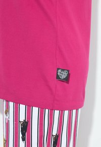 Fuksjowy bawełniany T-shirt z boczną metką, zestawiony z białymi szortami w paski, zdobionymi czarnymi i brązowymi wzorami psów.