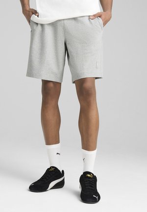 Chálare gris de algodón con un ajuste relajado, bolsillos laterales y un pequeño acento de logo. Llevado con zapatillas negras y calcetines blancos.