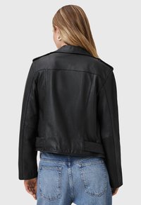Giacca in pelle nera con collo strutturato, due tasche laterali e un design aderente. La vista posteriore mostra una texture liscia e dettagli sulle spalle.