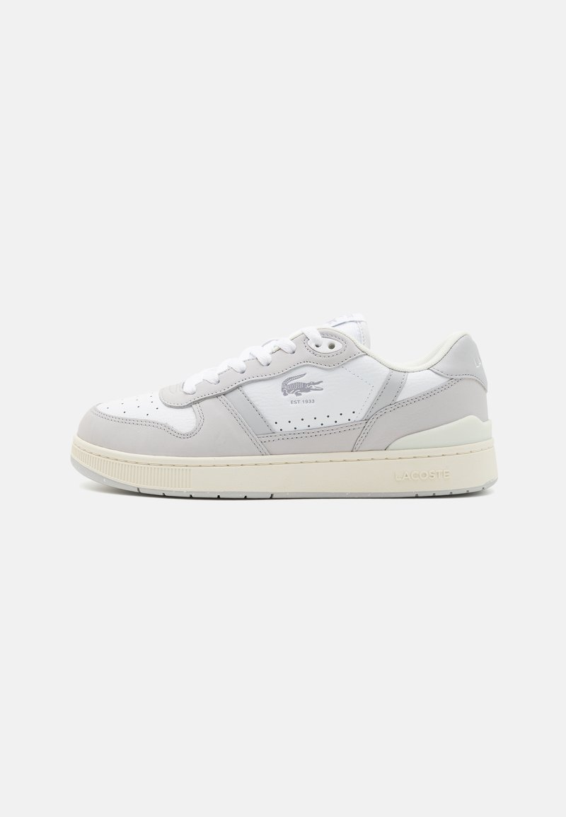 Sneakers Lacoste z białą skórzaną cholewką z szarymi akcentami, perforowanymi detalami, płaskimi sznurówkami i teksturowaną gumową podeszwą.