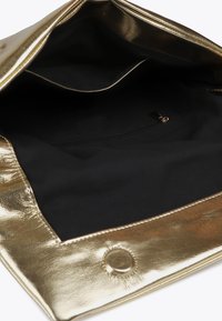 Zlatá metalická kabelka částečně otevřená, odhalující černý interiér s kapsou na zip. Důraz na lesklou texturu a detaily okraje kabelky.