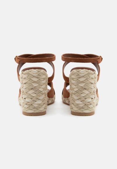 Sandales compensées en daim marron avec bride à la cheville, talons épais en jute tressée et semelles en caoutchouc texturées, vues de dos sur fond blanc.