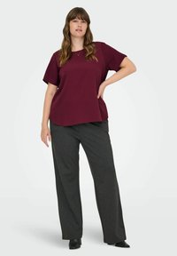 Mörkröd kortärmad topp med rund halsringning, tillsammans med löst sittande, mörkgrå byxor. Slät tyg med en avslappnad passform och mjuk textur.