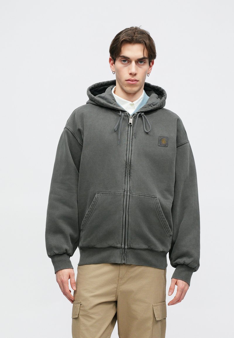 Felpa grigia con zip, cappuccio con coulisse, tasche frontali e polsini a costine. Realizzata in tessuto morbido, presenta un logo ricamato sul petto.