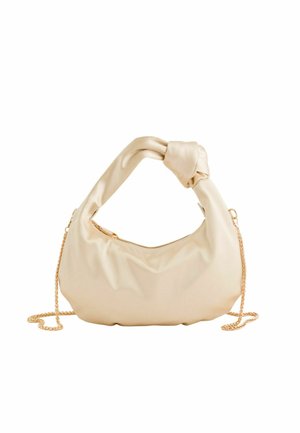 Weiche beige Lederhandtasche mit verdrehtem Griff und goldenem Kettenriemen, vor weißem Hintergrund dargestellt.
