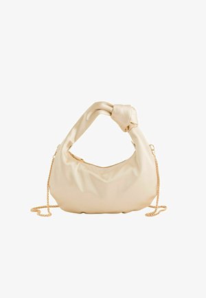 Weiche beige Lederhandtasche mit verdrehtem Griff und goldenem Kettenriemen, vor weißem Hintergrund dargestellt.