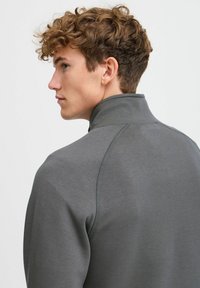 Gray high collar pullover sweatshirt with a smooth texture, raglan sleeves, and subtle stitching details along the seams.