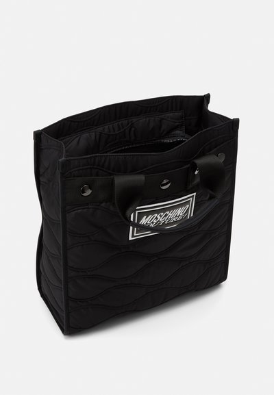 Borsa tote nera trapuntata con superficie texturizzata, dotata di doppio manico superiore, tasca interna con cerniera e un'etichetta logo bianca sulla parte anteriore.