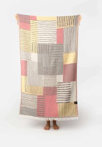 Textile blanket featuring a patchwork design with colors gray, pink, yellow, and white. Striped and block patterns with fringed edges.