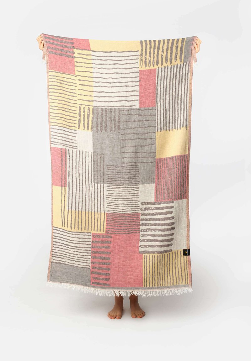 Plaid in tessuto che presenta un design a patchwork con colori grigio, rosa, giallo e bianco. Motivi a righe e a blocchi con bordi frangiati.