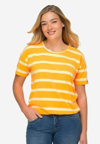 Camiseta de mangas cortas y cuello redondo en rayas naranja brillante y amarillo pálido. Material de algodón suave con corte relajado. Combinada con jeans azules.