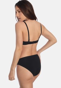 Zwarte bikini set met een eenvoudig ontwerp. De top heeft dunne verstelbare bandjes en een haaksluiting aan de achterkant, terwijl de high-waisted onderkant volledige bedekking biedt.
