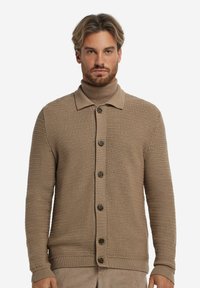 Ljusbrun stickad cardigan med krage, knappstängning fram och ribbade ärmslut. Texturerat tyg med ett vävt mönster.