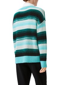 Striped sweater in teal, black, and white. Soft texture with a loose fit and a ribbed hem. Features varying horizontal stripes of different widths.