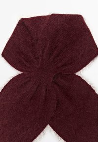 Sciarpa lavorata a maglia color bordeaux con una texture morbida e pelosa. Presenta una grande forma a fiocco creata da sezioni di tessuto sovrapposte.