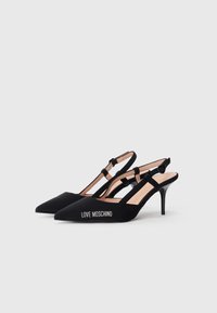 Cumpărați pantofi cu toc slingback negri, cu vârfuri ascuțite, textură din satin, curele subțiri la gleznă și cu branding "LOVE MOSCHINO" pe lateral.