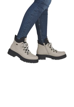 Beige Stiefeletten mit schwarzen Akzenten, strukturiertem Lederobermaterial, rundem Zehenbereich, Schnürverschluss vorne und robusten schwarzen Sohlen; mit seitlichem Reißverschluss.