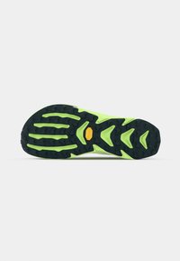 Semelle extérieure en caoutchouc noir et vert néon avec de profonds crampons de traction. Présente un logo jaune proéminent et des rainures stylisées pour une adhérence et une flexibilité optimales.
