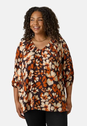 Blouse florale marron foncé avec des motifs orange et crème, présentant un décolleté en V et des manches bouffantes 3/4 avec des détails froncés.