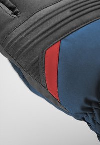 Svart och blå vadderad handske med en texturerad yta, med en röd detalj och ribbat mönster på den svarta delen.