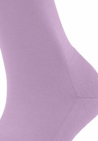 Chaussette lilas claire en tissu extensible et lisse. Présente un design sans couture avec un renfort au niveau des orteils et une texture légèrement côtelée.