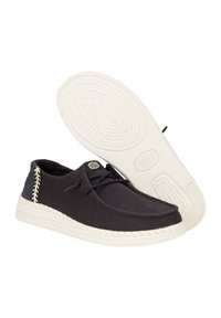 Scarpe in tessuto nero con tomaia testurizzata, dotate di suola in gomma bianca e dettagli intrecciati sul lato. Inclusi lacci e etichetta con logo.
