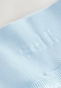 Heled sinise tekstuuriga ribakangas, millel on reljeefne tekst. Pehme struktuur, horisontaalsed jooned ja peene sära loovad taktiilse välimuse.