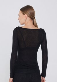 Haut noir à manches longues en tissu léger et transparent ; doté d'un large col et d'une coupe ajustée avec une texture lisse.