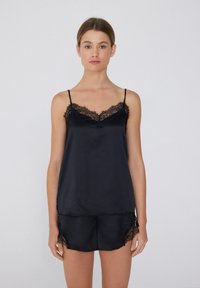 Ensemble en satin noir composé d'un camisole et d'un short, avec dentelle sur le col et l'ourlet. Bretelles ajustables et texture douce. Design classique de pyjama.