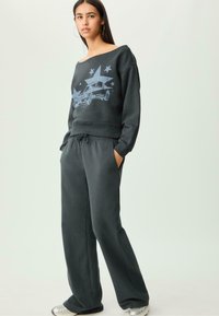 Donkergrijze sweatshirt en bijpassende broek, met een grafische afbeelding van een blauwe auto en ster ontwerp, gemaakt van zachte stof met een relaxte pasvorm.